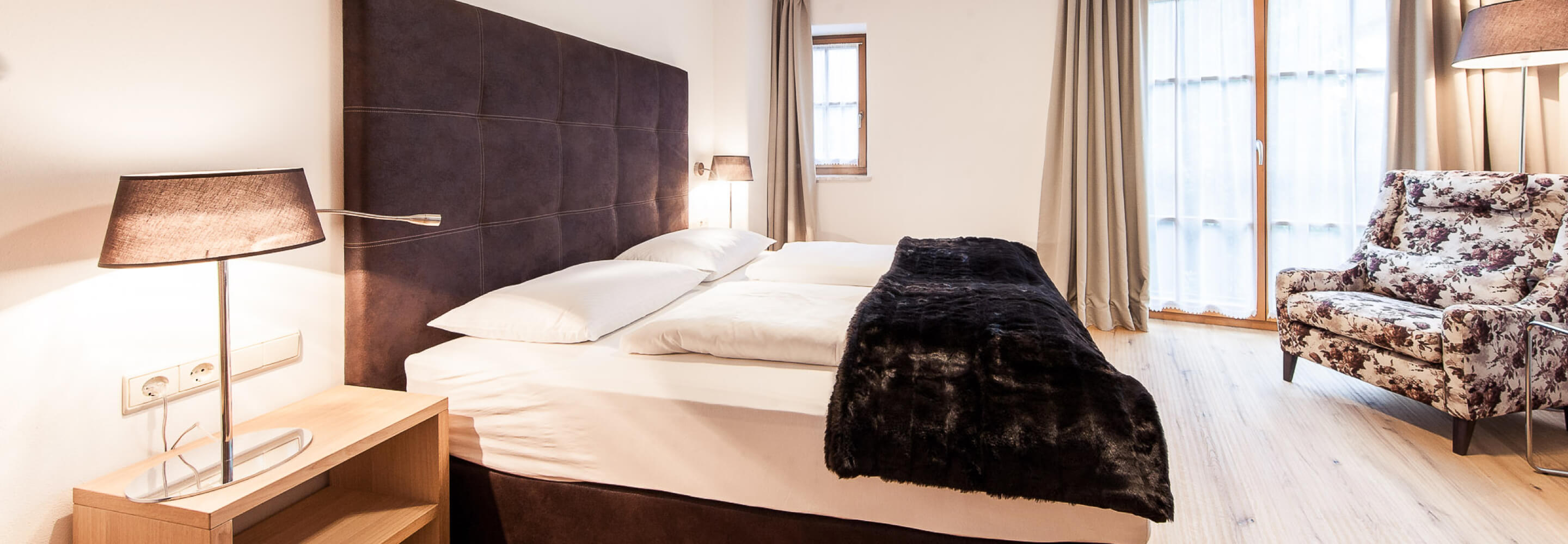 Hotelzimmer mit schönem braunen Bett und gemütlichem Sessel